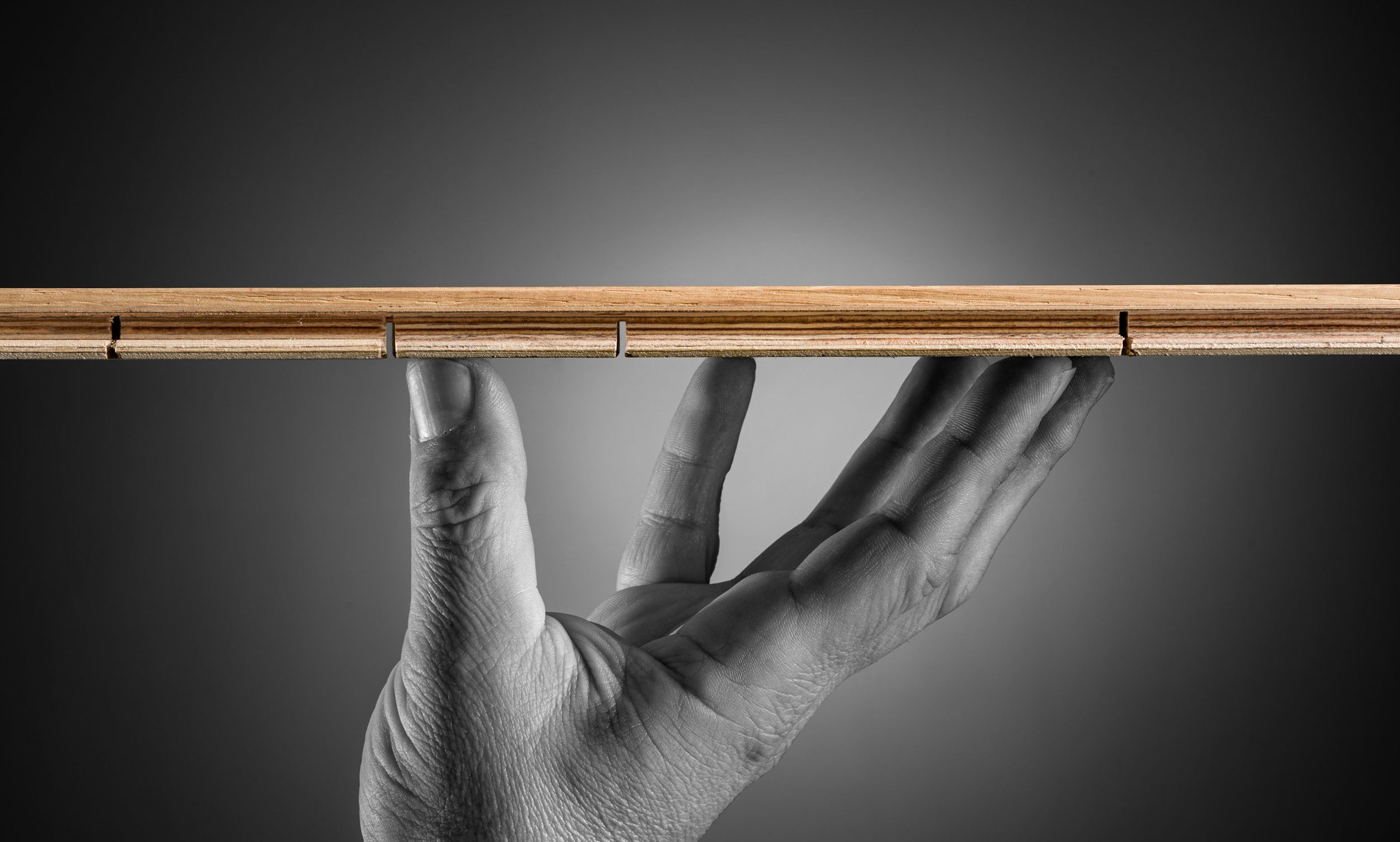 Una mano sostiene una tabla de madera maciza