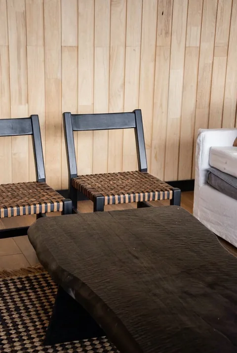 Detalle: sillas de estructura negra y mesa de madera ahuecada