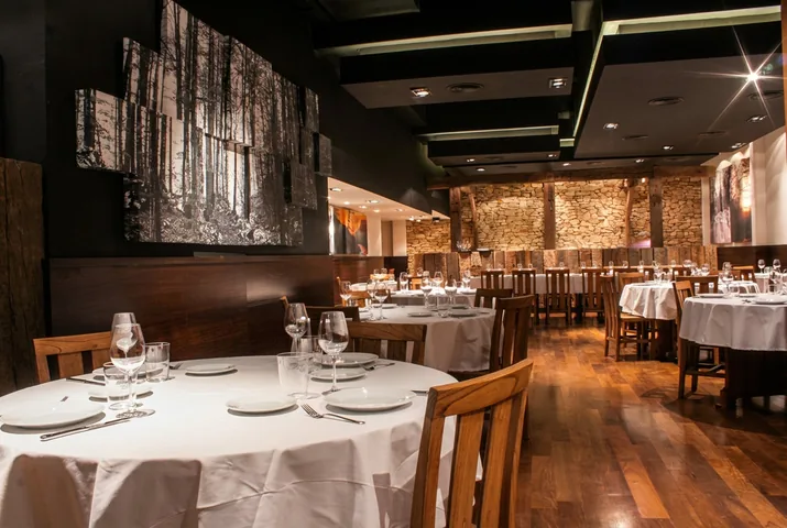 Salón con mesas redondas y muro de piedra