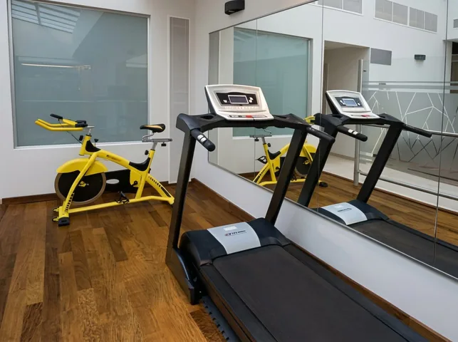 Gimnasio con piso de madera y espejo de pared completa