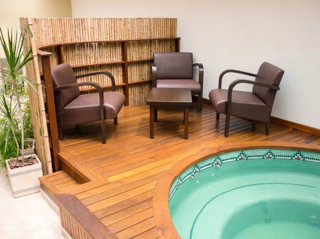 Estar del spa sobre deck de madera, con sillones y jacuzzi