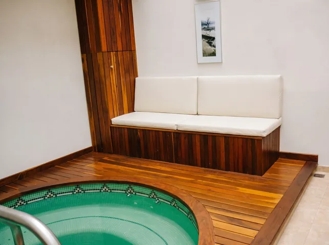 Banco revestido en listones de madera junto al jacuzzi