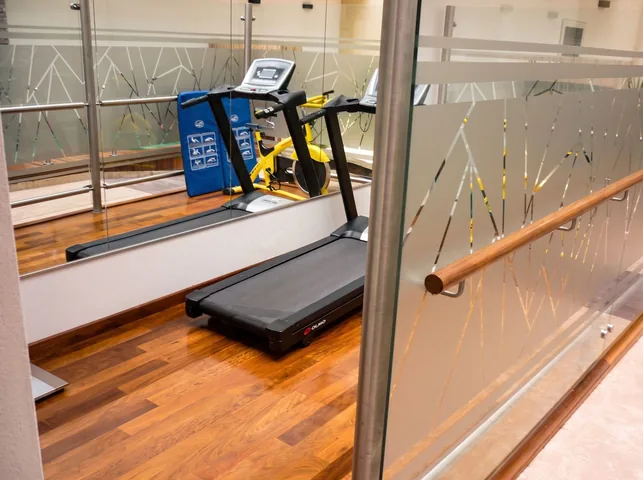 Gimnasio con piso de madera y mampara de vidrio