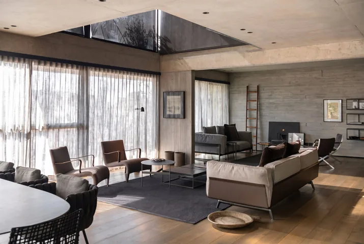 Living con piso de madera, sofás y luz natural bajo el lucernario