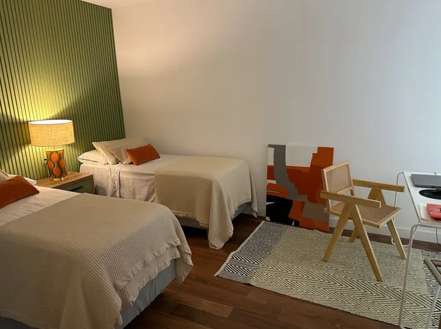 Dormitorio con dos camas, pared verde de listones y piso de madera