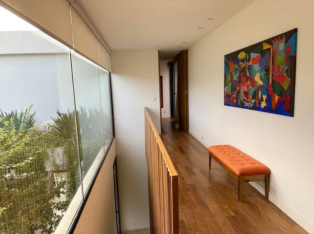 Pasillo de la planta alta con piso y baranda de madera