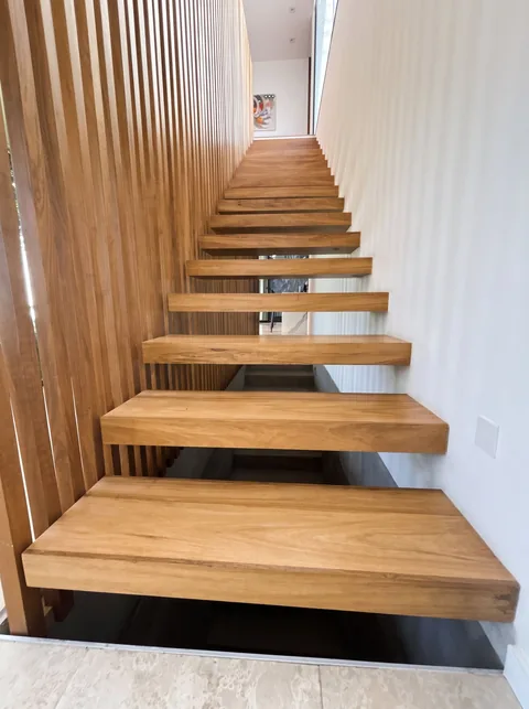 Escalera flotante con pasos de madera y celosía lateral