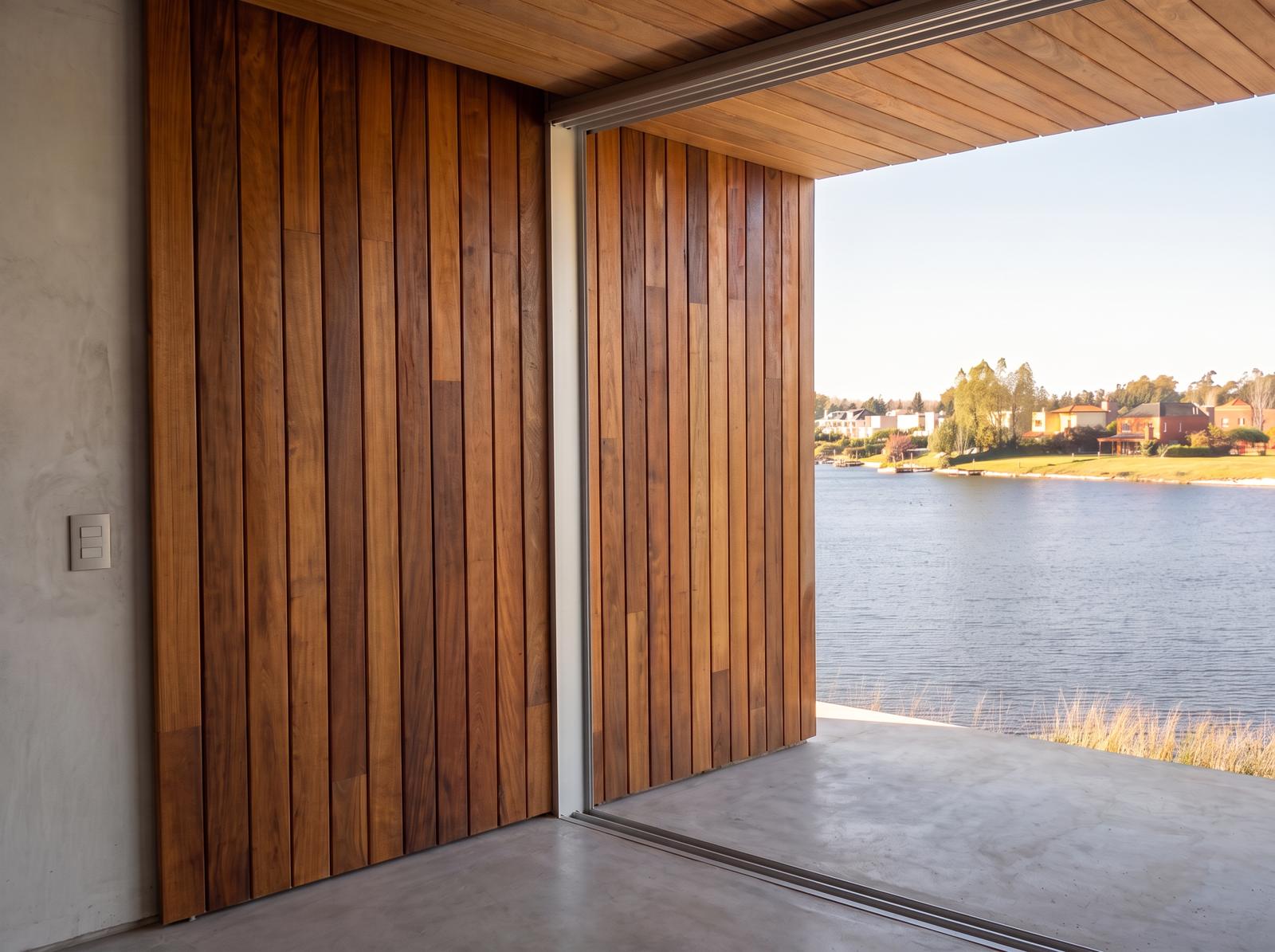 Revestimiento de listones de madera junto al ventanal con vista al lago