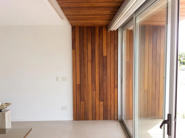 Living con muro de madera y ventanal corredizo