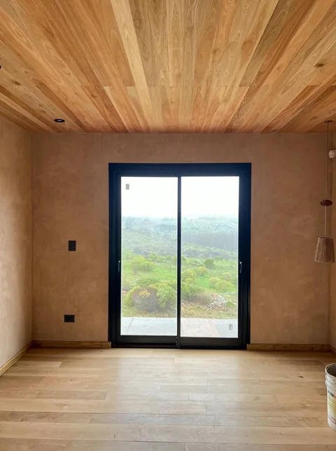 Habitación con cielorraso de madera y ventana al paisaje