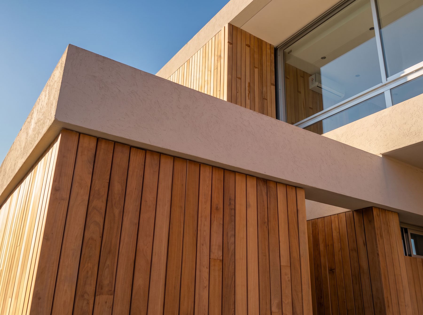 Fachada con revestimiento de listones verticales de madera y volúmenes de hormigón